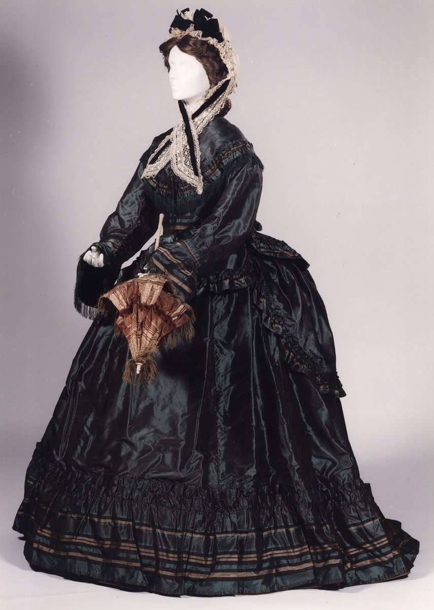 In the early stages of the fashion for the bustle, the fullness to the back of the skirts was carried quite low and often fanned out to create a train.