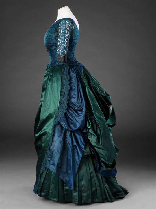 By the 1880s, the soft curve bustle dresses of the early 1870s were replaced with a new distinct silhouette featuring a severely tailored figure from the front and added draperies to the back.