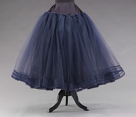 These voluminous skirts with their yards of excess fabric presented a sharp counterpoint to the practical skirts and clothing rations of the war years.
