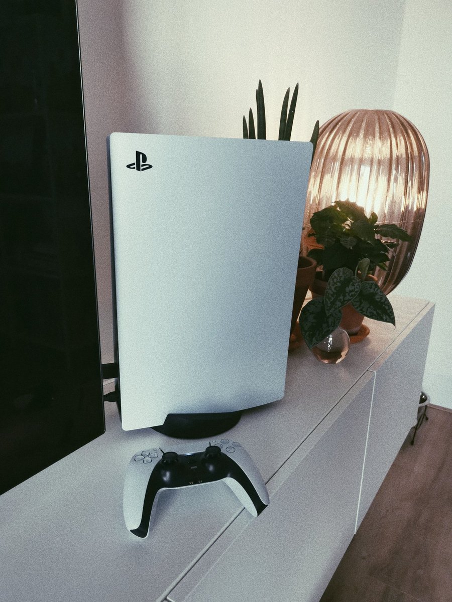 The PS5 controller and console in vertical position next to my TV