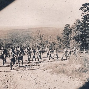 The track was just a bulldozed trail up the side of the mountain, complete with rocks, potholes, and a rain gulley that ran down the middle. Many falls occurred and many broken and sprained limbs were suffered. Pictured is G Co, 506th PIR10/