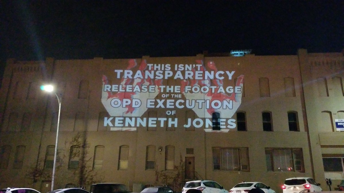 Projector image on a nearby building - "This isn't transparency, release the footage of the OPD execution of Kenneth Jones"