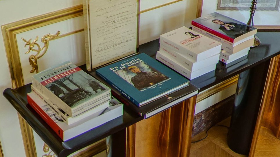 Enfin détour par la console en arrière-plan, sur laquelle se lit comme une histoire de France par rebond : Clémenceau, De Gaulle (I know), Mitterand et ... l'œuvre complet d'Emmanuel Macron. Difficile de faire plus clair, à défaut de faire cohérent. 22/30