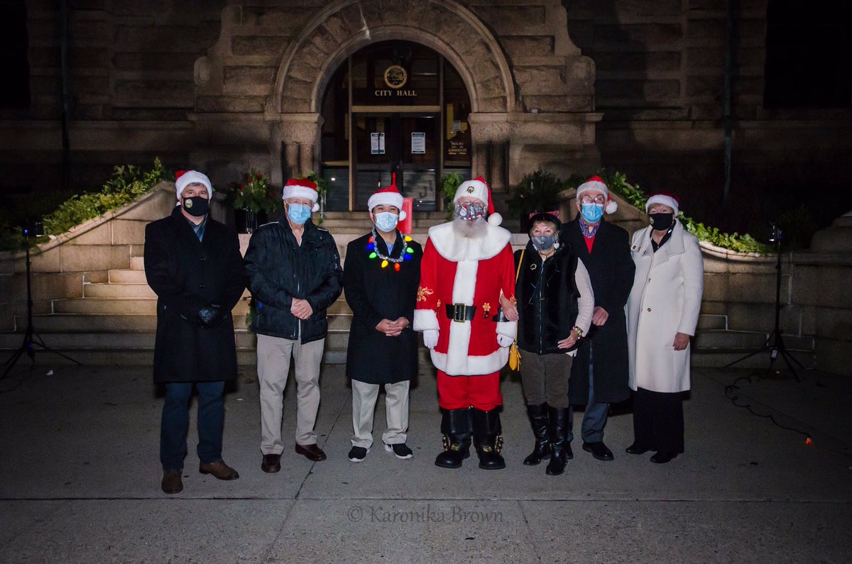 SokharyChau's tweet photo. Lowell City Hall is lighted!  I’m the one wearing a mask and Santa hat.  #LowellCityofLights https://t.co/fX7t3JYk89