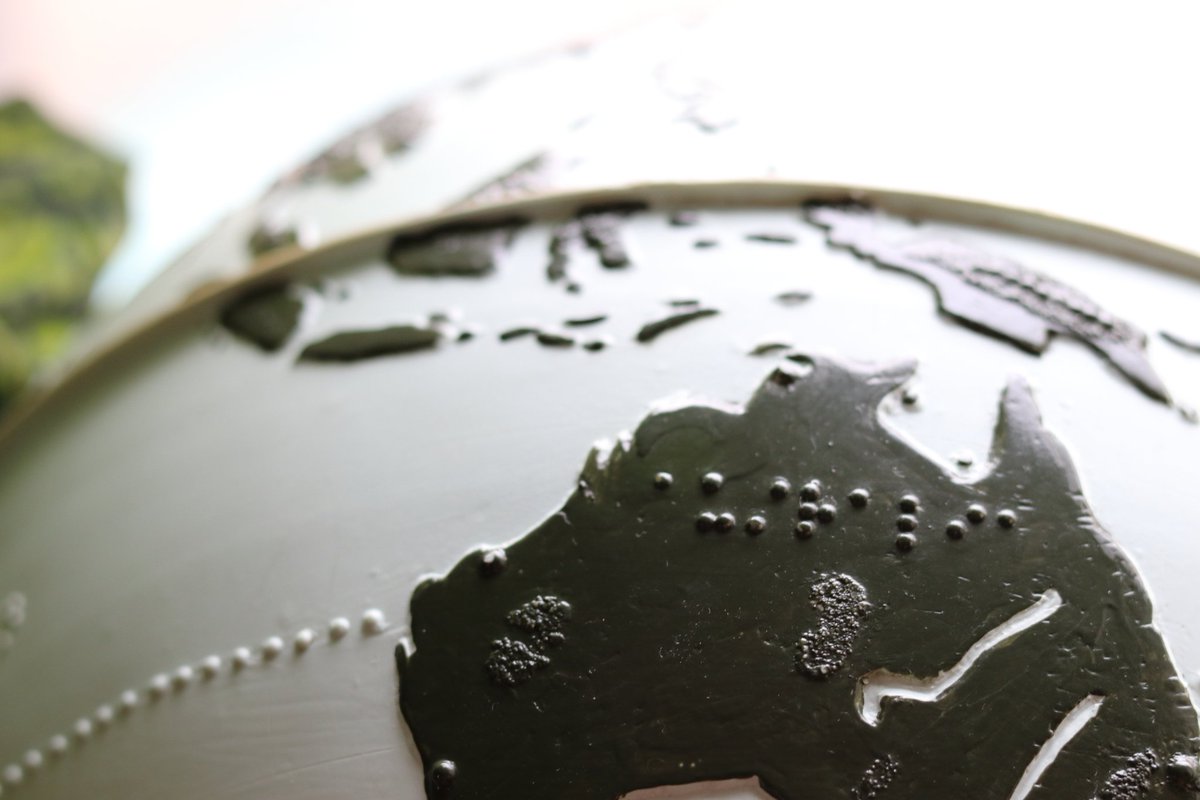 A closeup view of the globe showing Australia. Raised dots show the location of the Tropic of Capricorn. Braille labels for Australia. The equator is a raised line.