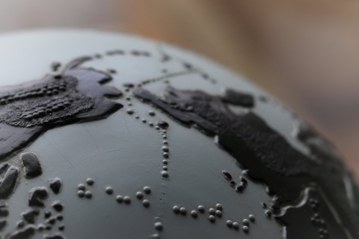 Photo of a globe showing the Arctic ocean and international dateline with Alaska and Western Russia (Kamchatka). Braille labels the Arctic ocean  and the international dateline is indicated with raised dots. Major mountain ranges and cities are also raised.