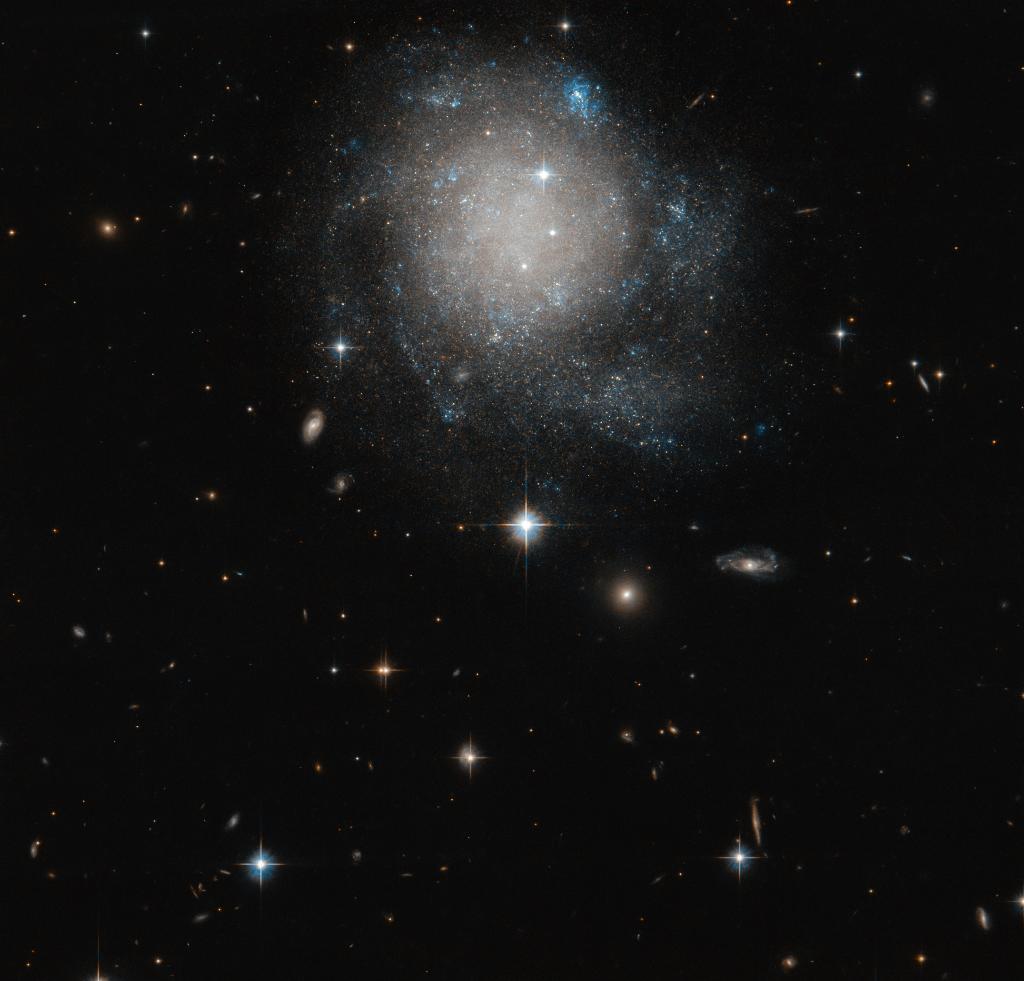 NASA's tweet photo. Nom nom nom 😋 Our @NASAHubble Space Telescope captured a delicious glance of what resembles a cosmic cinnamon bun. Bluer stars sprinkled around the edges highlight the regions where new stars are most likely being formed: https://t.co/Uc4r0suWOm https://t.co/mmg02e6jkk