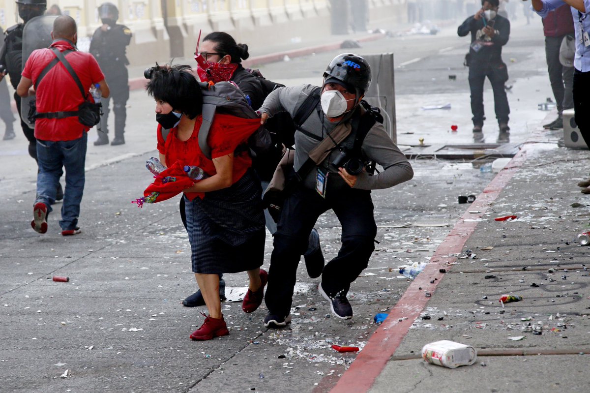 El fotógrafo <a href="/johanordonez/">Johan Ordóñez</a> ayuda a levantarse a una mujer lastimada durante el enfrentamiento entre la Policía y manifestantes, frente al Congreso de Guatemala el 21 de noviembre de 2020. #efefotos