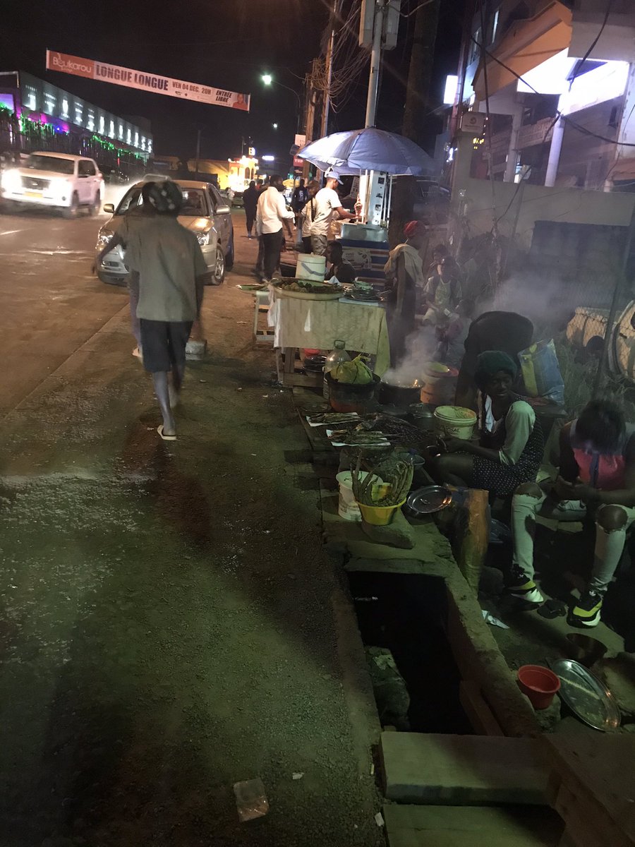 KevineMogo's tweet photo. C’est dimanche, il est 19h30. Au carrefour bastos, il fait bon vivre. Entre le Black and white et le  restaurant le JC il n’y a pas que des grands milieux( restaurant 4,5 étoiles), mais aussi des tournes dos, où sont en vente poissons, beignets et viande braisée,@Baba_WAME https://t.co/M0jCm1vC1y