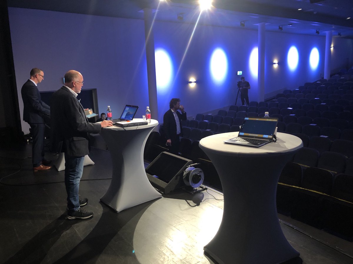 Achter de schermen van de algemene ledenvergadering. In een lege theaterzaal met leden die online zijn.