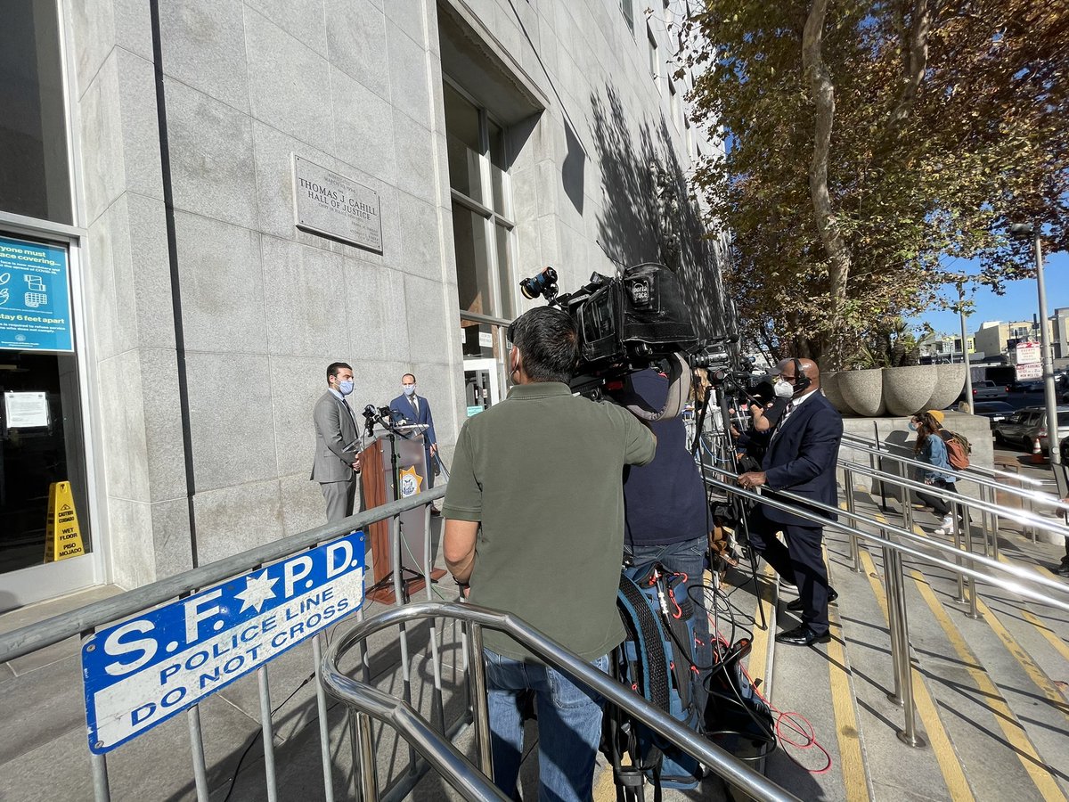 Media cover the announcement behind SFPD barriers set up outside the Hall of Justice (I think they were already there because of covid restrictions)