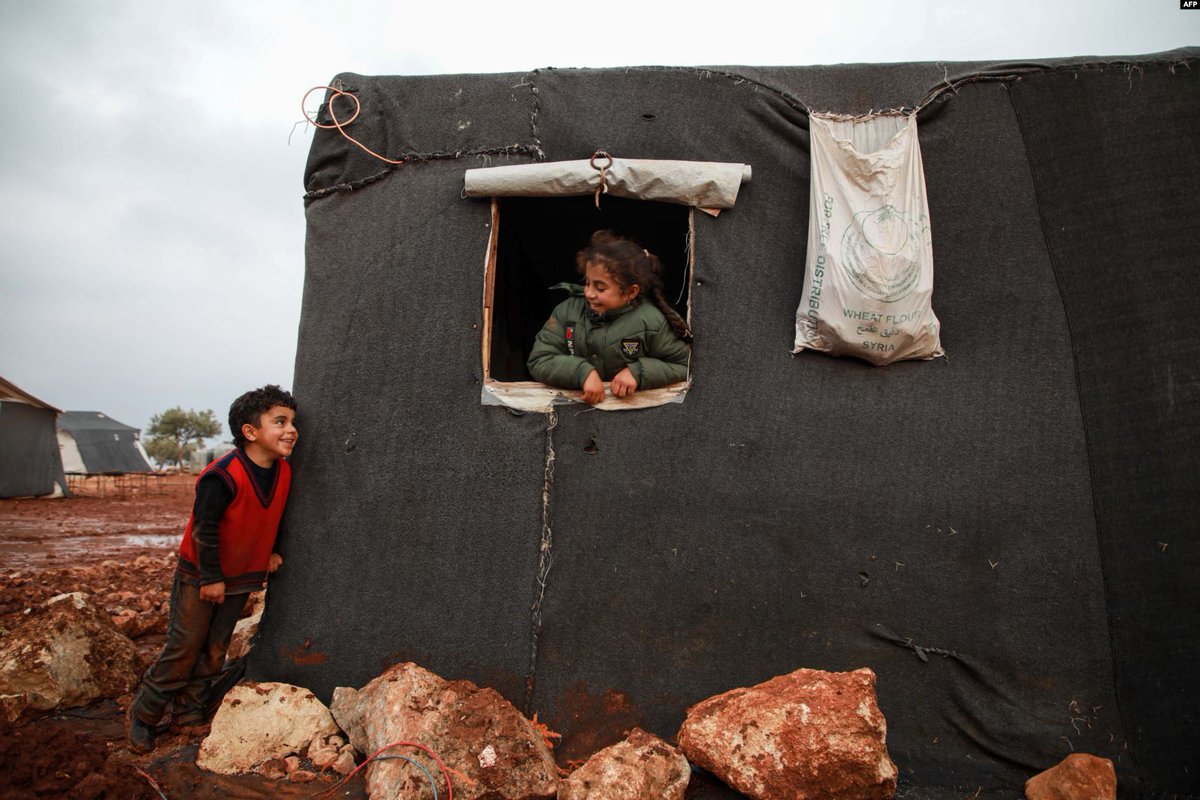 Looking at each other through the windows of their tents, a boy and a girl in a flooded camp, near the village of Kelly, northwest of Idlib, Syria