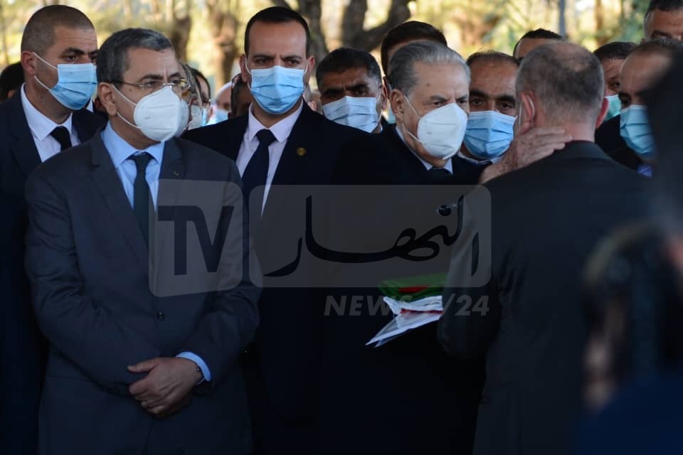 لحظة تسليم صالح قوجيل العلم الجزائري لنجل المجاهد الراحل السعيد بوحجة