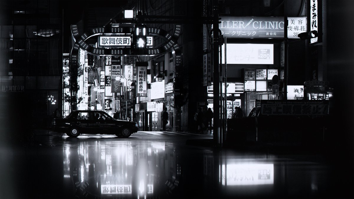 A black and white photograph of Tokyo's red light district: Kabukicho. A taxi passes by the iconic neon gates. There is a reflection captured in the camera of the overhead neon signs, typically in a burning red color. There's a noir feeling to the image. People can be seen walking through the scene.