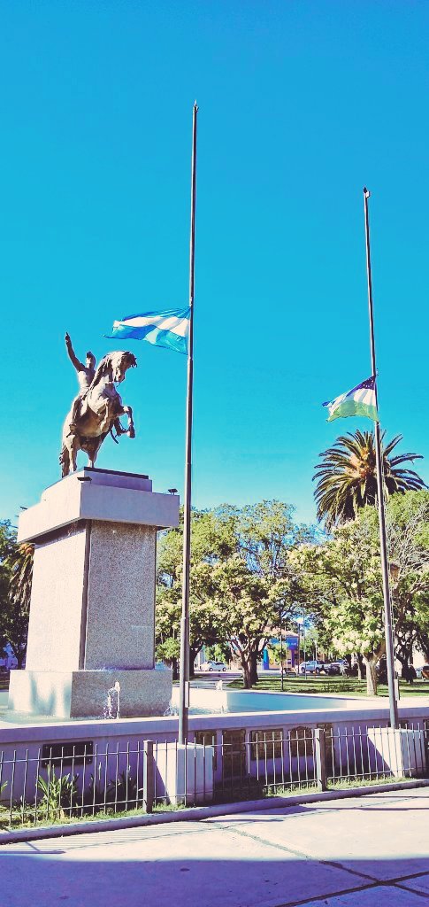 Periolance's tweet image. Al igual que en todo el país en la Plaza San Martin de Viedma, Capital de Río Negro, las banderas nacional y provincial flamean a media asta por el duelo nacional por el fallecimiento el ex futbolista y DT Diego Armando #Maradona