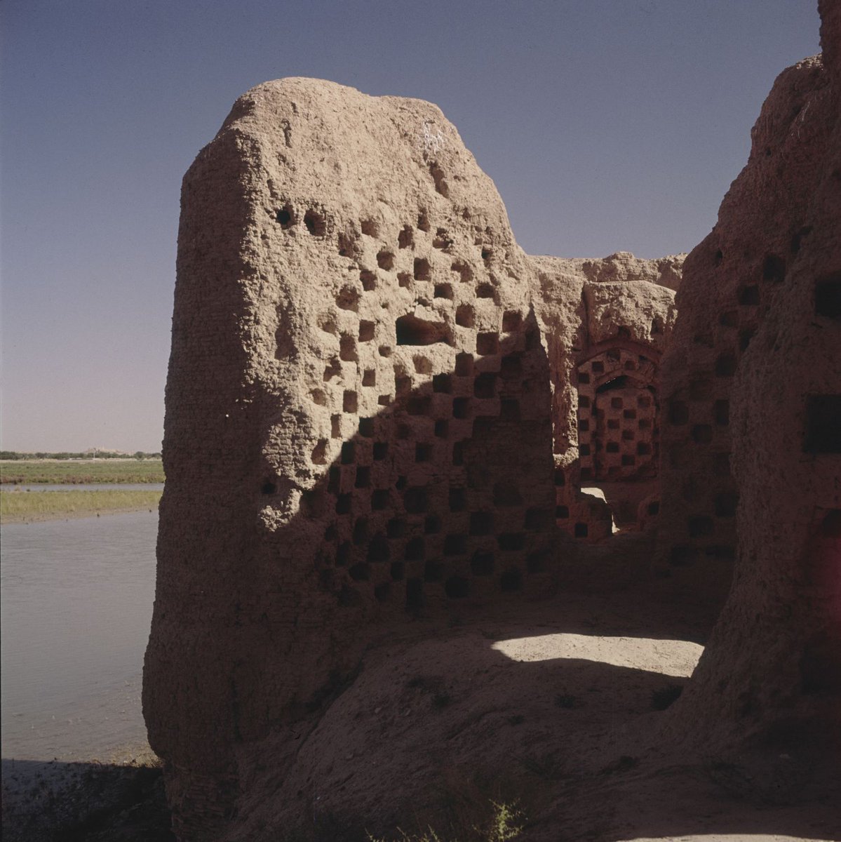 which are buttressed with circular corner towers, once rose to a height of about sixteen meters. The palace is organized on two floors divided into quadrants with barrel-vaulted corridors running along the central axes, intersecting at a large central light-well.