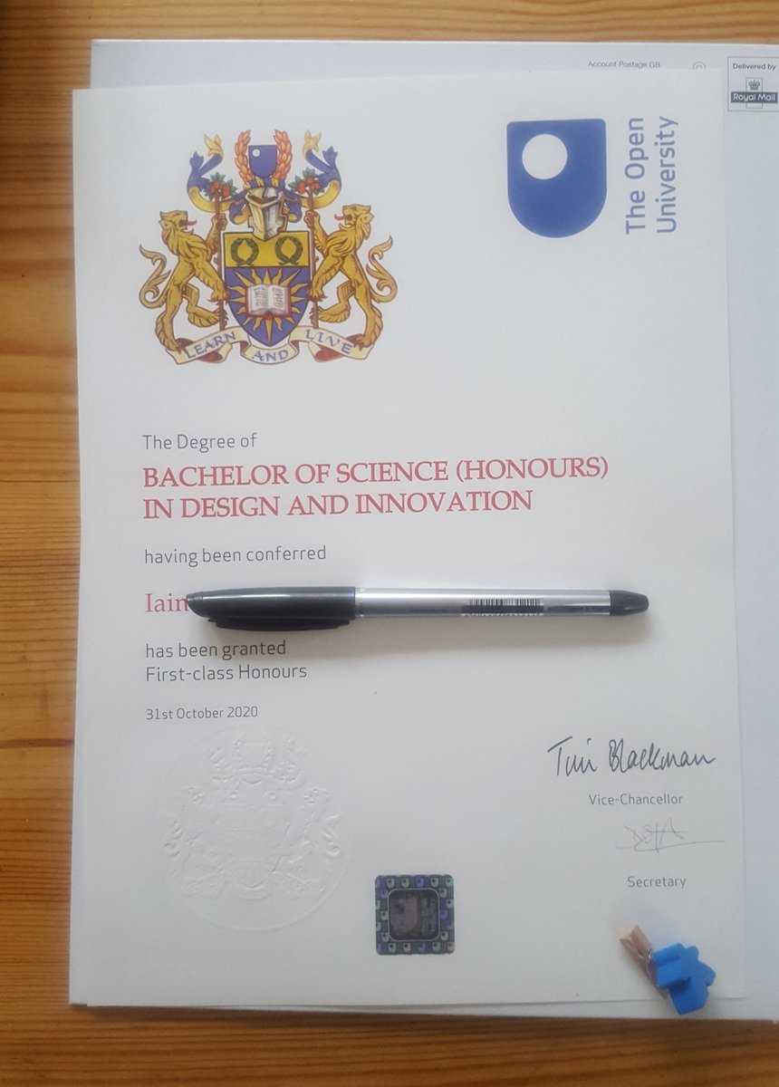 A photo of a degree certificate on a coffee table. The paper has an embossed crest, the open university logo and my name, plus the classification: first class