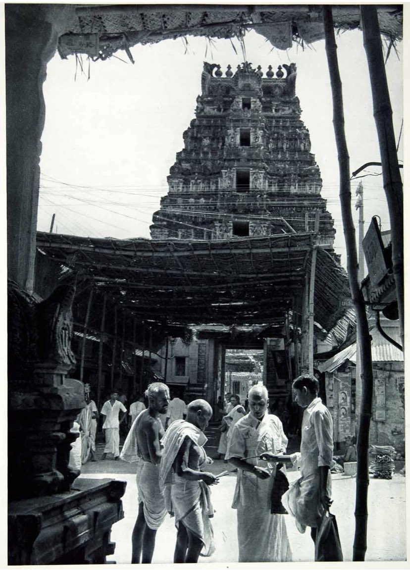 This is an original 1955 duotone rotogravure of a Brahmin buying pencils in the street in front of a temple at Srirangam, Tiruchirapalli, India.