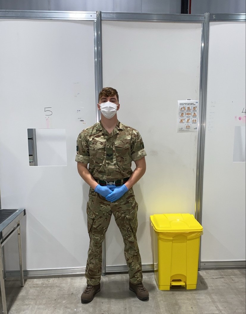 A soldier in protective gear stands in front of a cubicle