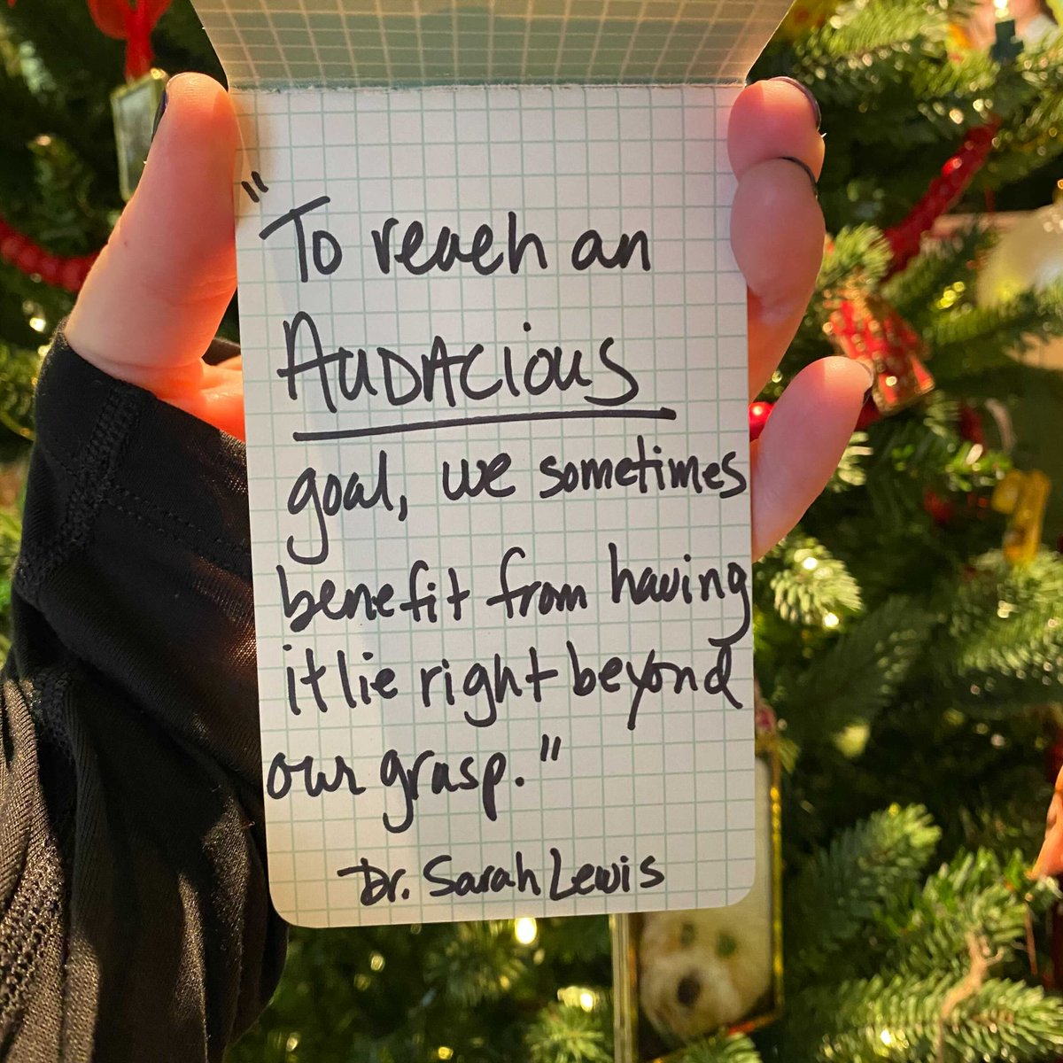 Brené holding a hand written note that says, "To reach an AUDACIOUS goal, we sometimes benefit from having it lie right beyond our grasp." - Dr. Sarah Lewis