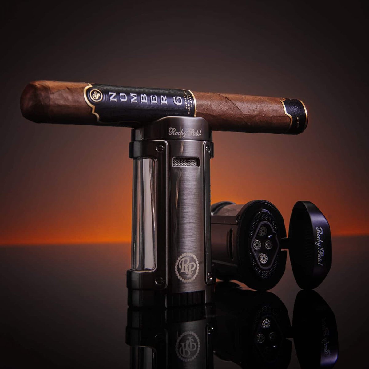 IN STOCK - <a href="/RockyPatelCigar/">Rocky Patel Premium Cigars</a> Odyssey Lighter.

Available in 3 colors, the Odyssey features 4 powerful blue-flame jets and a built in groove on the lid for your cigar. Odyssey also has adjustable flame height, a side fuel tank window, and includes a lifetime warranty.