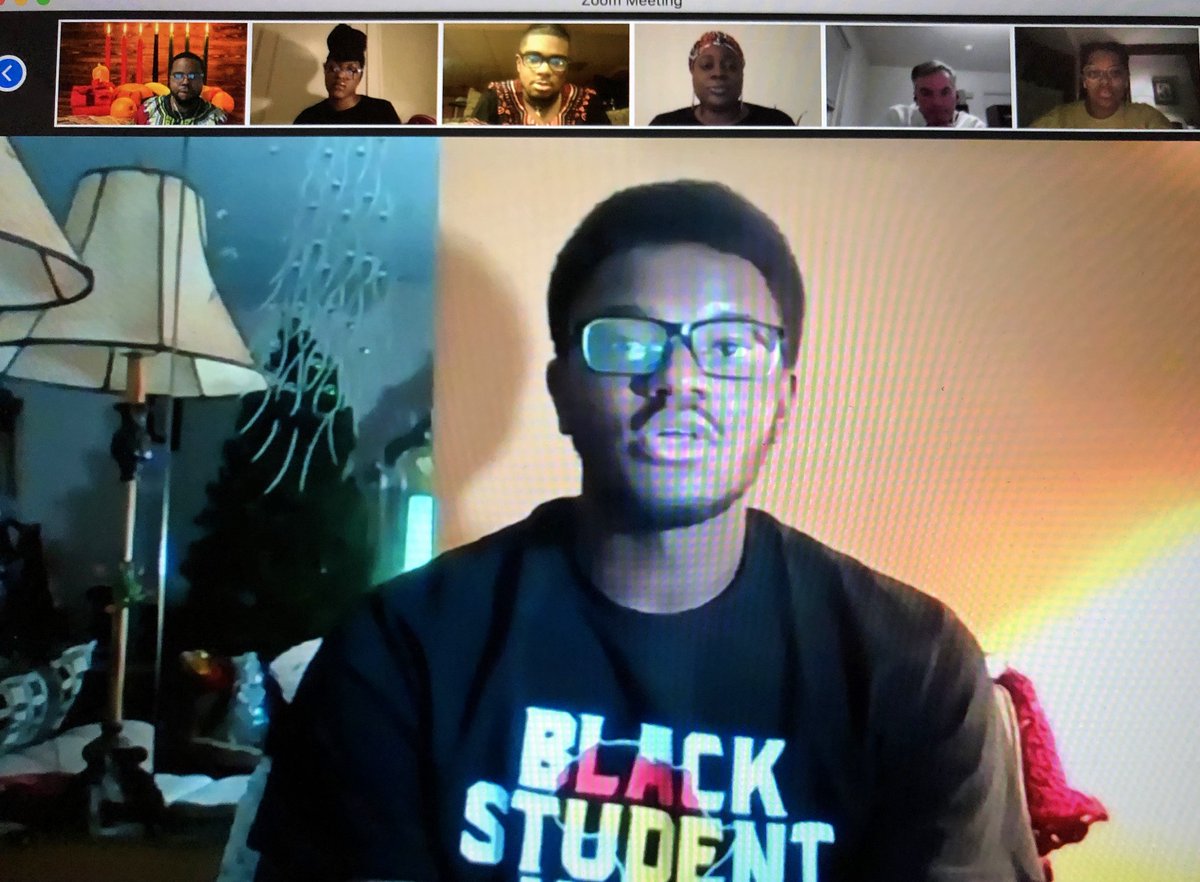 Student wearing a Black Student Union T-shirt speaking on a zoom call with 6 participants shown at the top of the screen