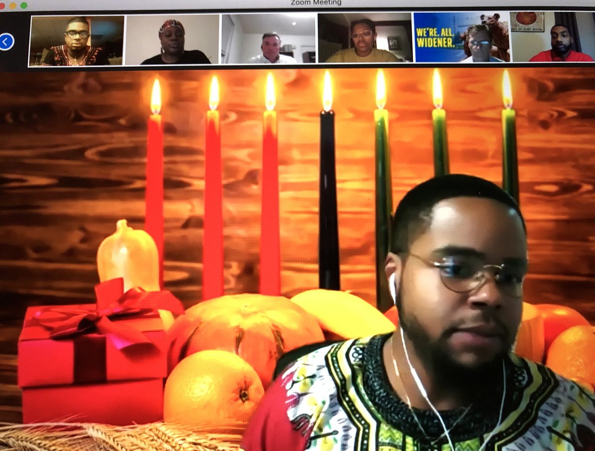 Justin Johnson speaking on a zoom call with a Kwanzaa virtual background featuring a lit kinara