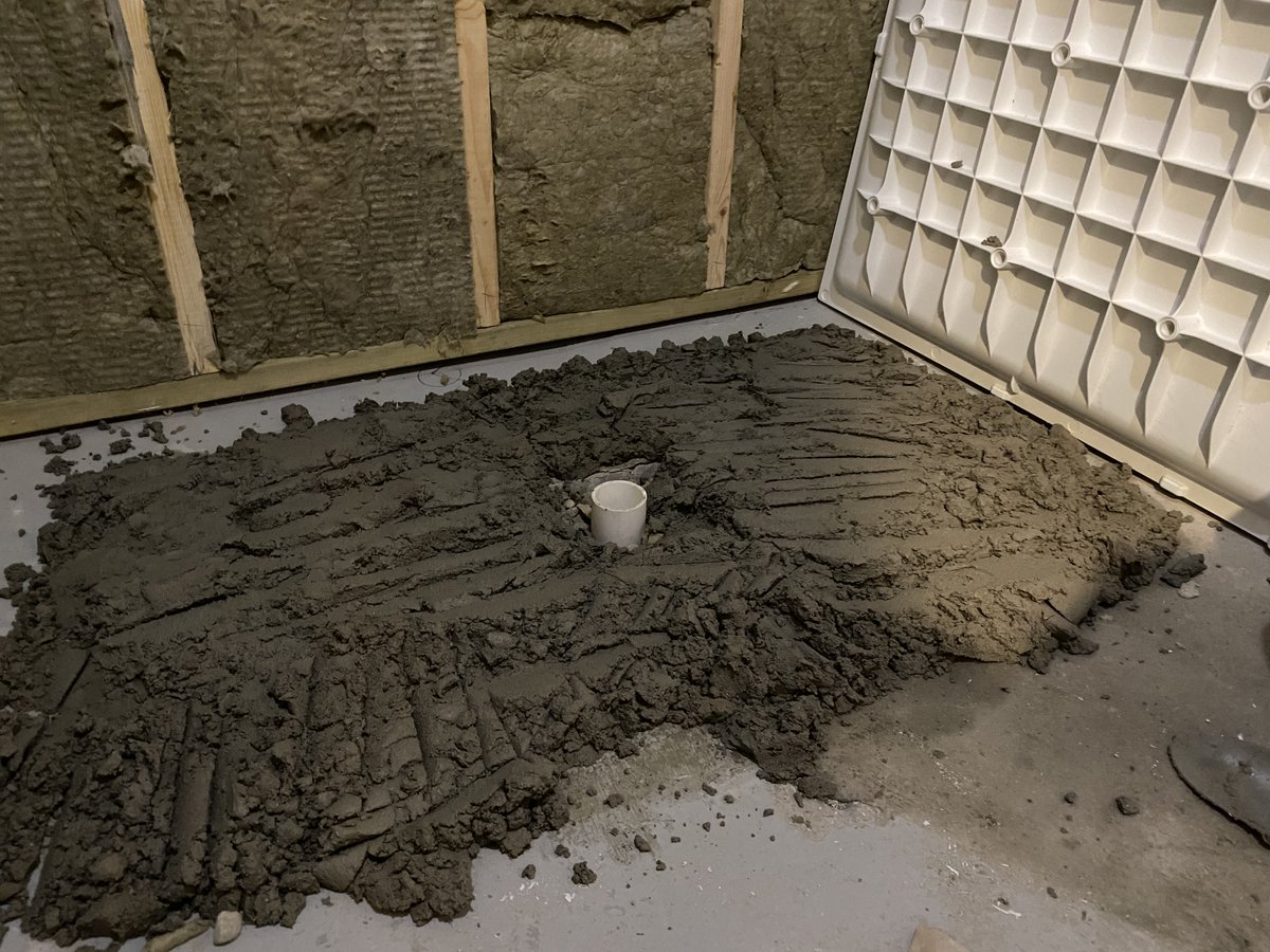 A bed of mortar cement spread on a concrete floor to a depth of approximately 2 inches 