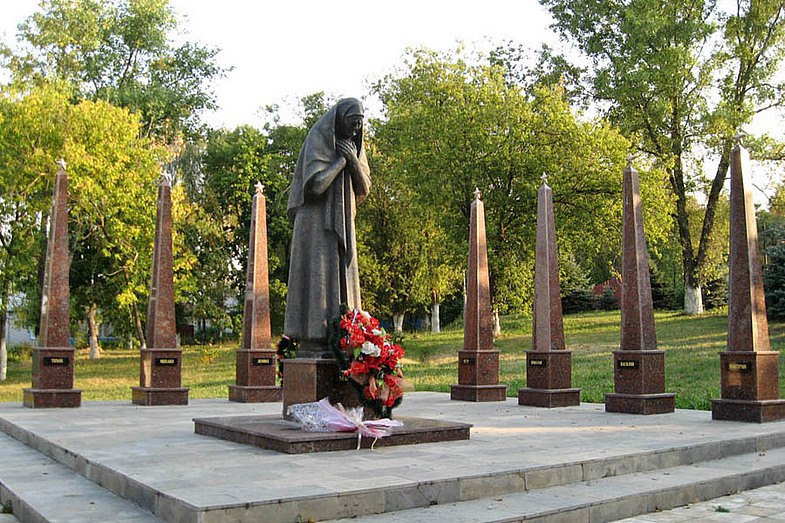 Простая русская женщина в платке сгорбившись в горе склонила голову, а вокруг размещены восемь обелисков с именами: Михаил, Дмитрий, Константин, Тихон, Василий, Леонид, Николай, Петр.
Это памятник в Задонске матери, Марии Матвеевне Фроловой, отдавшей ради Победы восемь сыновей.