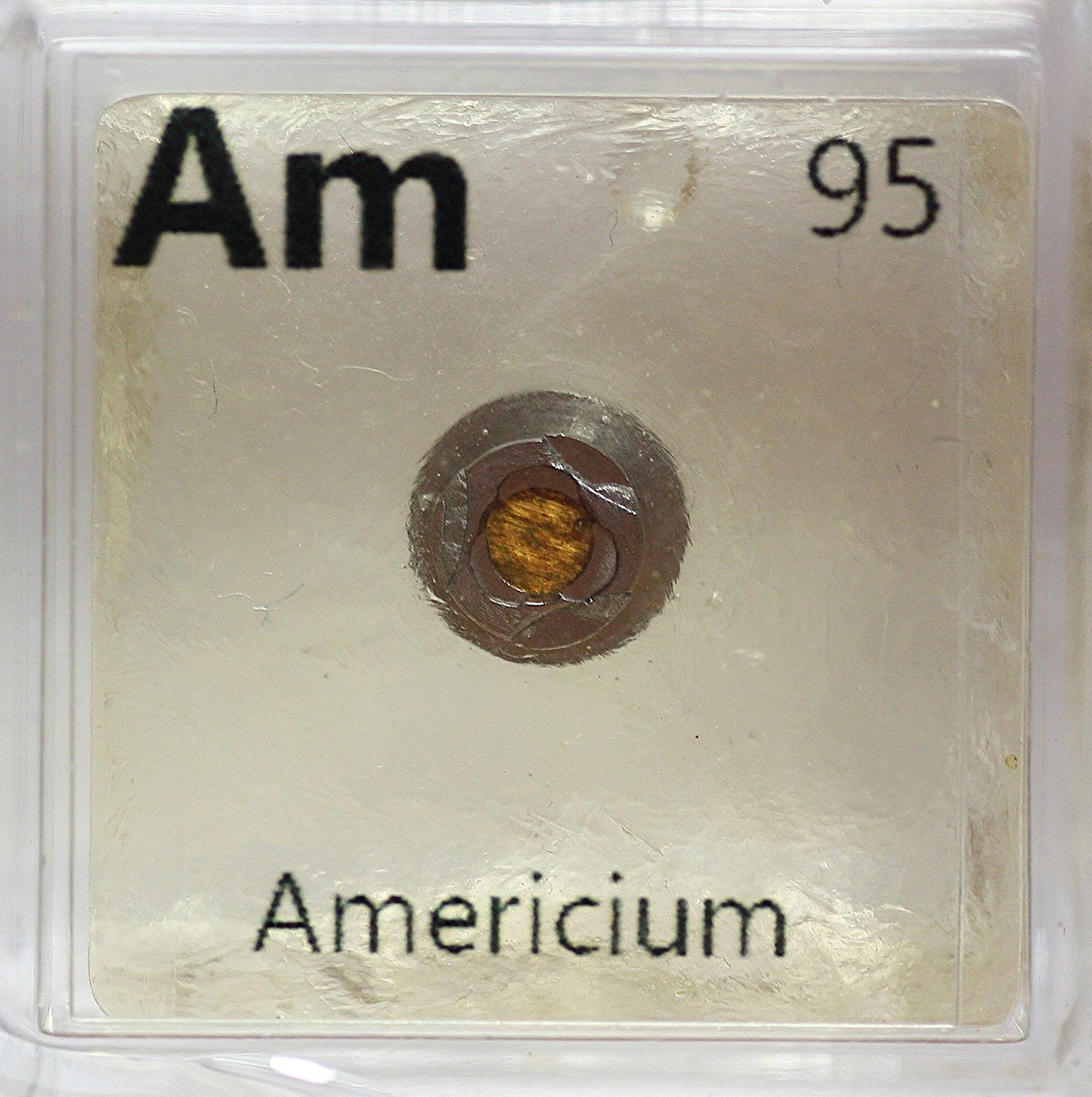 Neptunium and Americium  #elementphotos. At the heart of an ionisation-type smoke detector is a little button that contains a small amount of americium dioxide (AmO2). The Am241 (halflife 432 yrs) decays to Np-237 (halflife 2M yrs), and thus the Am is slowly being replace by Np.