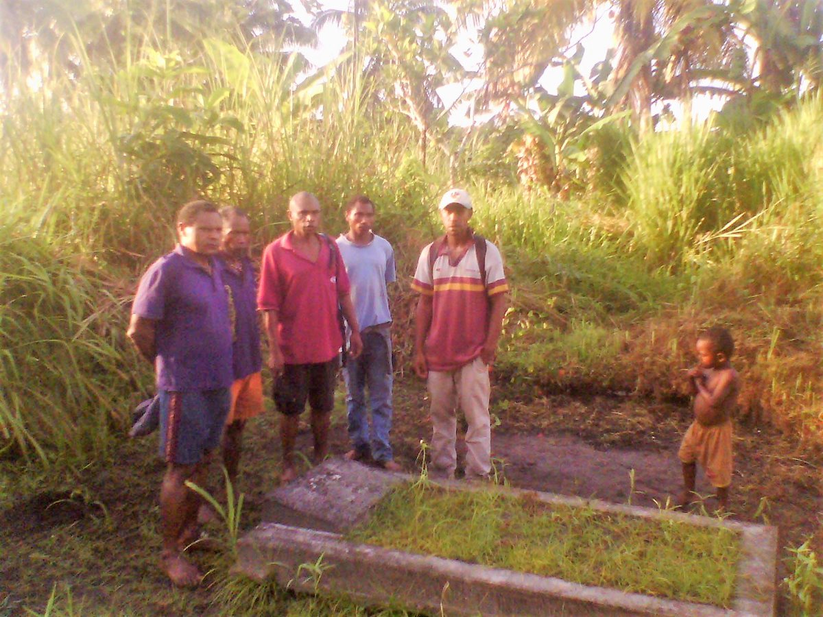 Men of Oimbari's extended family, including his only son Martin (in morone shirt) at his grave in 2013 with Wardman Ogamie, Chairman of Raphael Oimbari Foundation, at Hanau village, Ijivitari, Oro province.The Foundation seeks to develop the local Orokaiva community.FB photo.