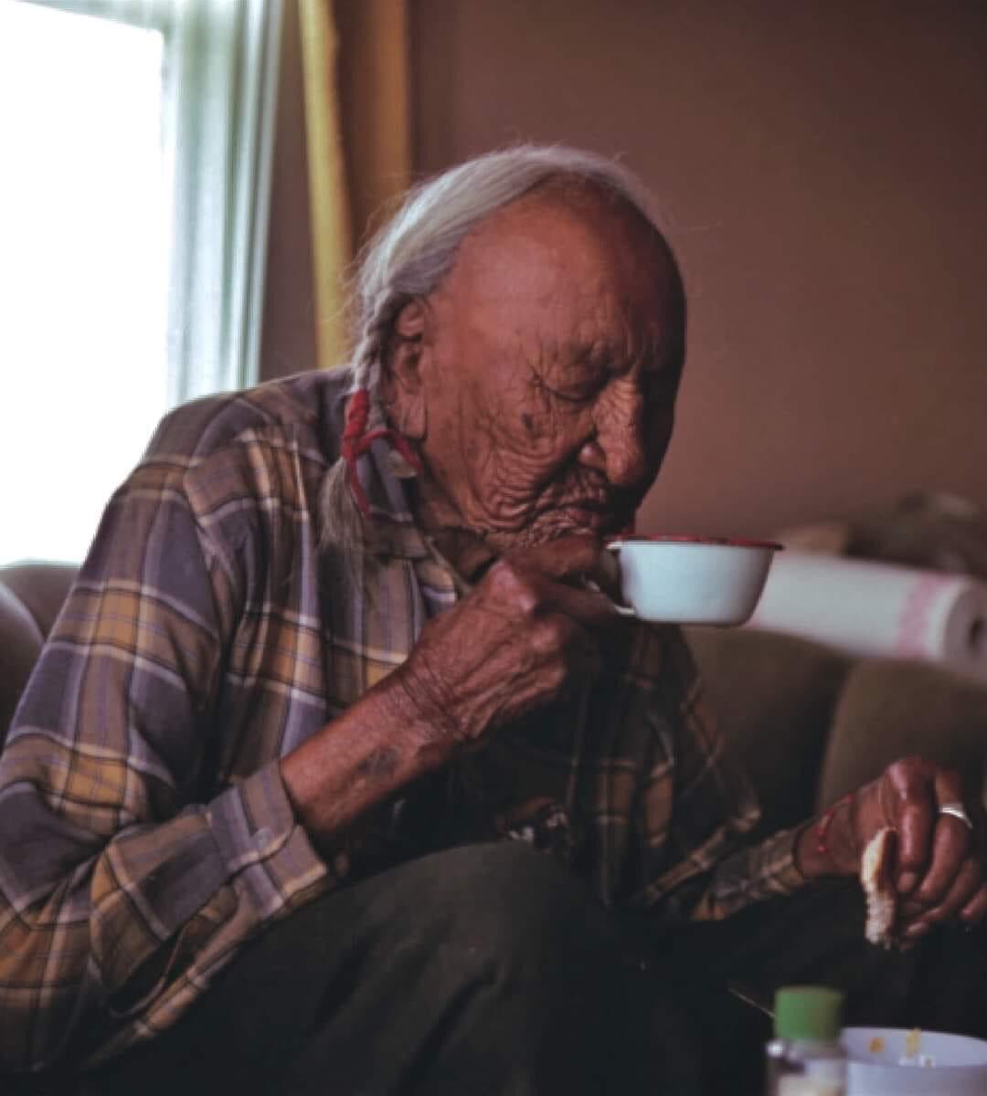 LakotaMan1's tweet photo. “1969, intimate portrait of Piikáni Blackfoot elder, James White Calf having coffee and bread for breakfast, seated on his favorite couch, in his home along Cutbank Creek. The dark circle on his right arm shows where a musket ball went through him during a battle in the 1880's.” https://t.co/LQ9jIDeWvk