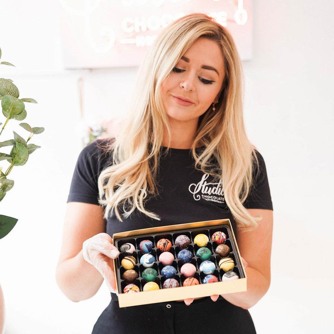 Owner of Studio Chocolate, Ellie Wharrad, holding a box of her painted chocolates.