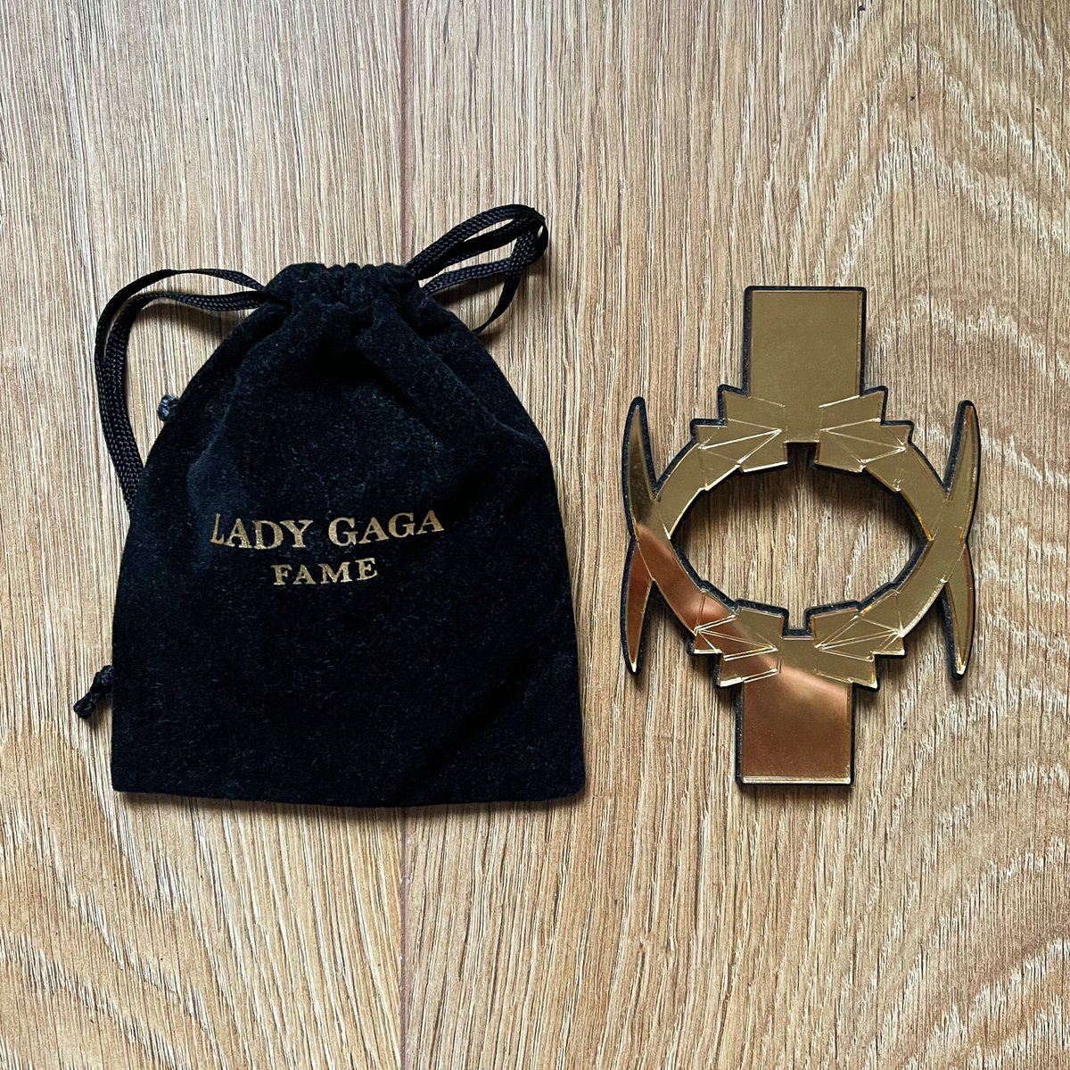 GagaManiaUK's tweet photo. Day 2. This is the employee badge covers that Harrods employees wore for Lady Gaga’s UK launch of her Fame perfume. It’s made from laser cut/etched gold mirror acrylic on black acrylic with matching velvet pouch with Fame branding. #GagaCollection https://t.co/VmojtDBnZg