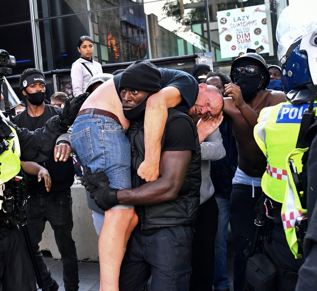 Protester Patrick Hutchinson carries an injured counter-protester to safety, near Waterloo station during a Black Lives Matter protest in London, Britain, June 13, 2020.  @REUTERS/ Dylan Martine