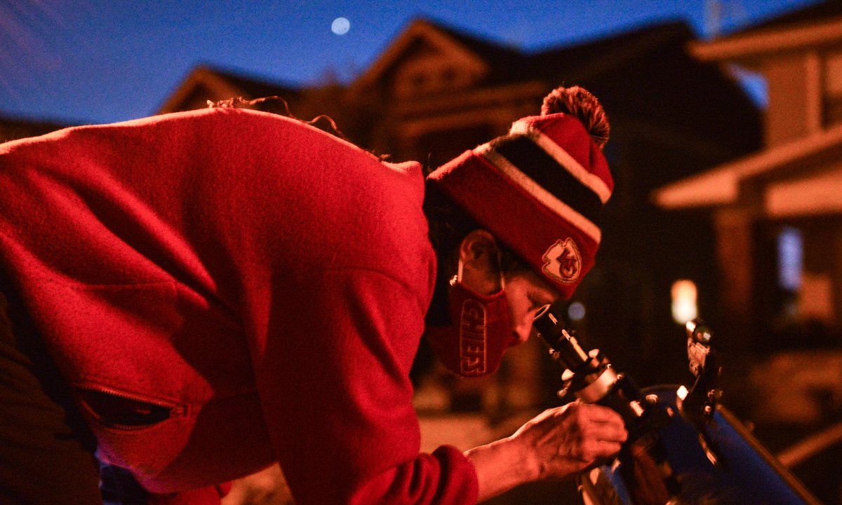 Elizabeth Bejan peers into a telescope trained on the Jupiter and Saturn conjunction appearing just above the rooftops of her neighbors Monday night. Hobbyist Rick Wohlfarth set up his telescope on Forest Street and invited neighbors to view the planetary alignment. 
<a href="/kcur/">KCUR</a>