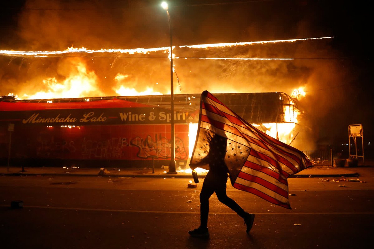 - May 28 -A protester carries an American flag upside down next to a burning building in Minneapolis. Protesters started rallying across the US after the death of George Floyd, a Black man who was killed in police custody in the city.  https://cnn.it/3lXJBdf 