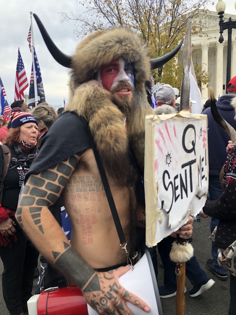 The QAnon presence today seems much more visible than last month’s rally, probably because there are fewer people. Even Arizona’s “Q Shaman,” who dresses in animal pelts and promotes QAnon, is here.