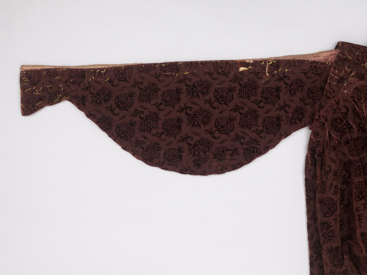 This is part of a woman’s loose gown, made in the early 17thC of Italian cut &amp; uncut mulberry-coloured velvet in a pattern of pomegranates &amp; gillyflowers. It features a style of sleeves known as ‘hanging’ &amp; was once decorated with two different types of silver lace. (V&amp;A)