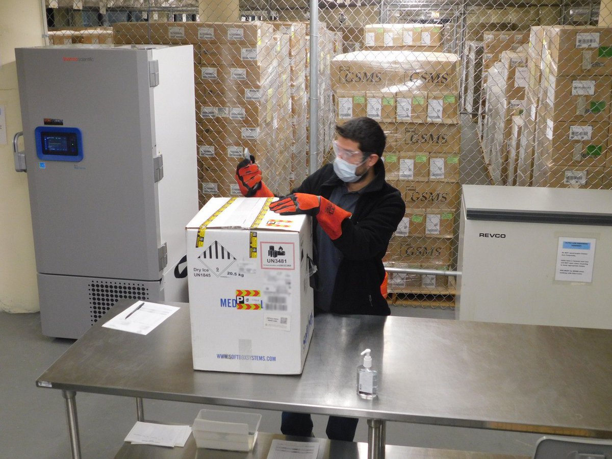 A man opens a box with COVID-19 vaccines.