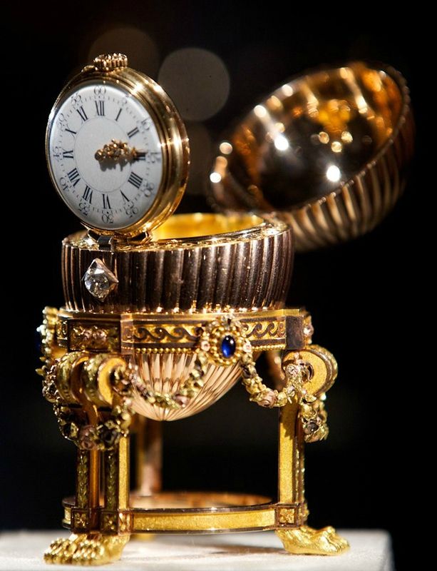 The egg was created in Louis XVI style and it consists of a solid 18K gold reeded case resting on a gold "annulus" (ring) with waveform decorations held up by three sets of corbel-like legs which end in lion's paws.