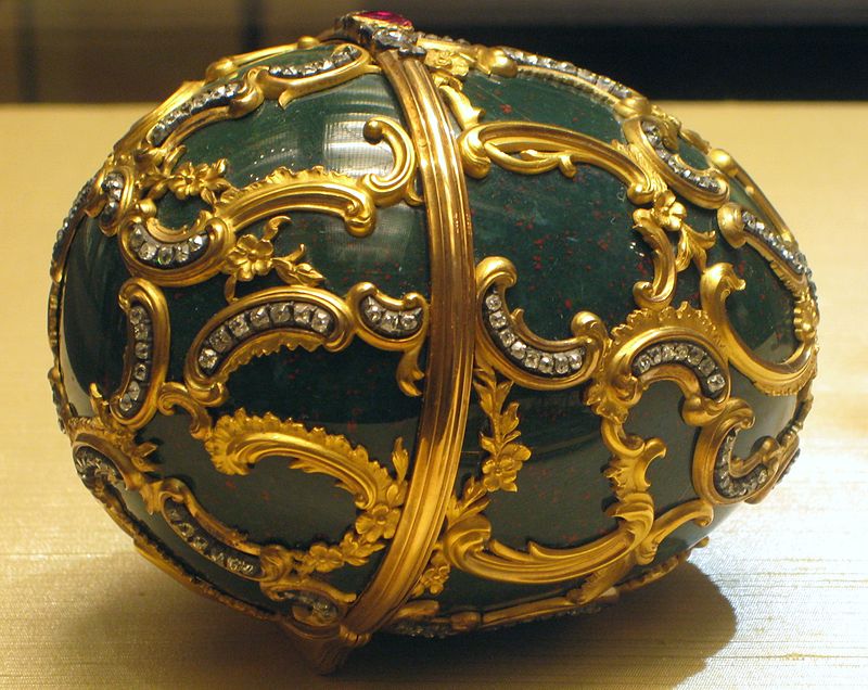 Carved from a solid piece of heliotrope jasper, also known as bloodstone, the Memory of Azov Egg is decorated in the Louis XV style with a superimposed gold pattern of Rococo scrolls with brilliant diamonds and chased gold flowers.