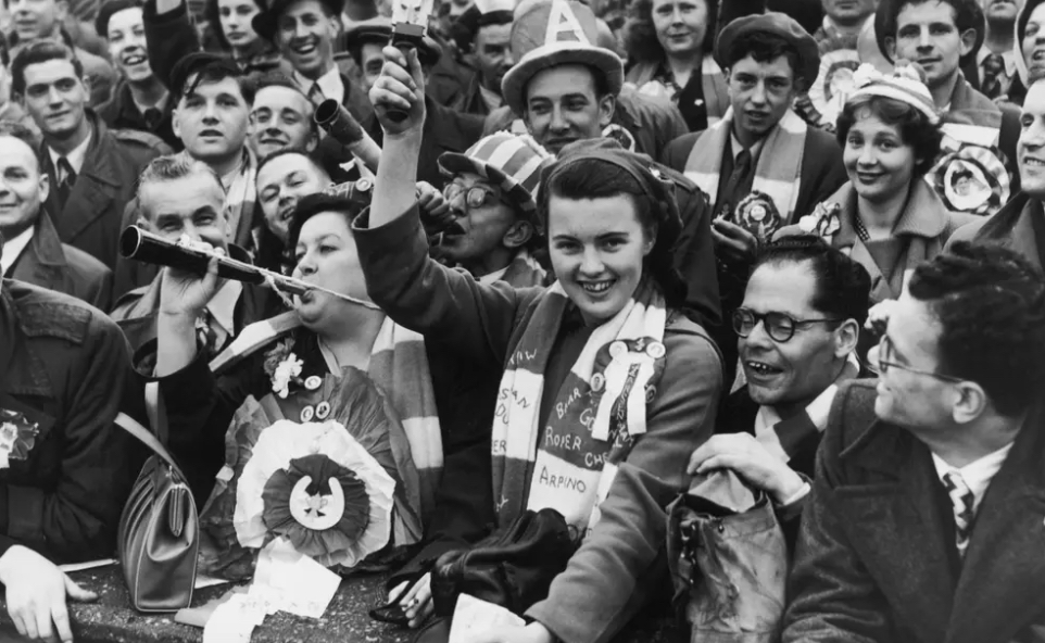 So to the 1950s, and yes this is trendy north London Gooners, and yes, the women are prominent, and the hats largely playful / comedic. But for the blokes, it's still shirt & tie & jacket.4/6