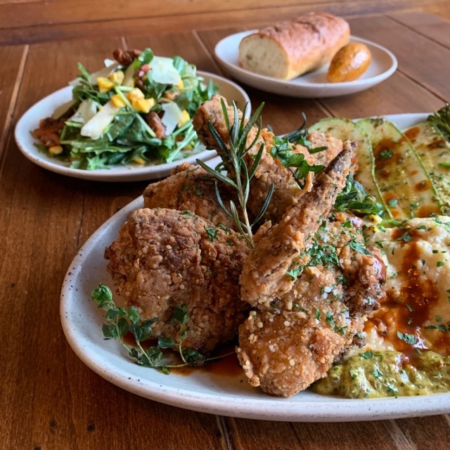 One of this week's dinner kits features oregano and rosemary buttermilk fried chicken (white and dark meat), creamy poblano polenta, seasonal grilled vegetables, housemade chipotle cider hot sauce and chimichurri. Choice of salad, Macrina potato baguette and chimichurri butter.