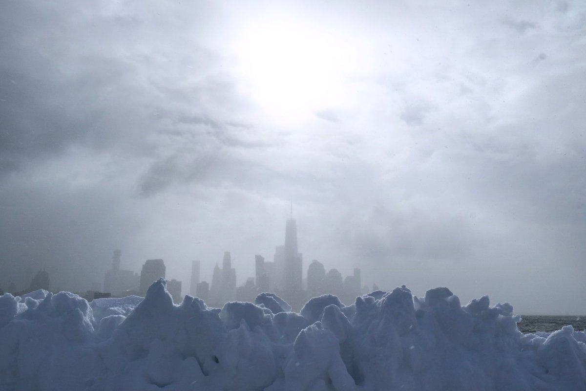 Snow falls as the sun appears over lower Manhattan and One World Trade Center in New York City as the storm begins to move  out from the city #newyorkcity #nyc #newyork <a href="/agreatbigcity/">A Great Big City</a> #snow