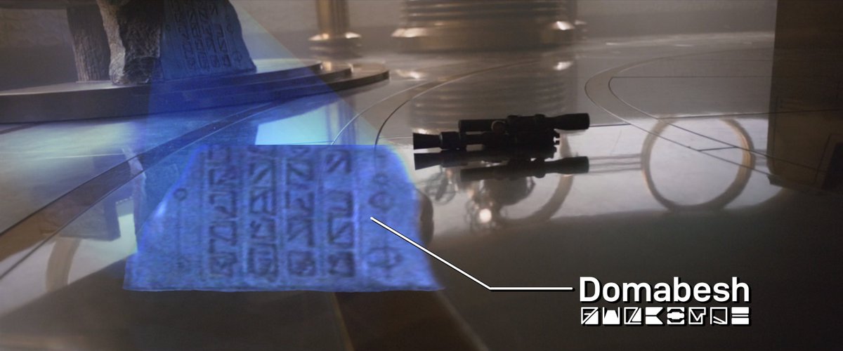 By enhancing the image, we can see that the stone base of Dryden's desk bears an inscription in Domabesh (a more ancient cousin of Aurebesh): 3/