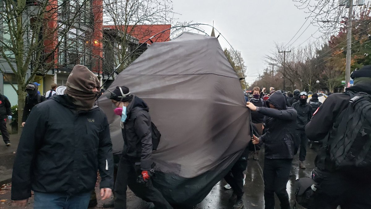 Protesters carry more tents out of the park. 1 person pulled their car up right in the middle of the action to help load someone's tent and belongings away.  #calanderson &ndash; bei  Cal Anderson Park