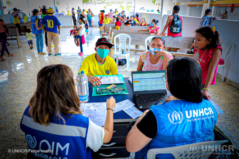 A family receives support from UNHCR workers at a migrant center during COVID-19