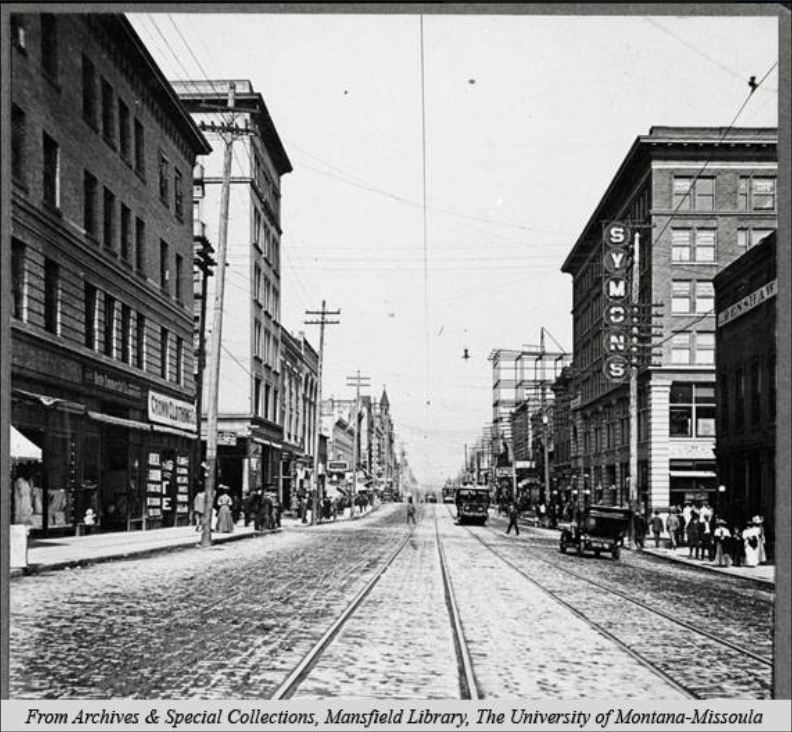 Looking east on Park Street, Butte, Montana. Streetcar tracks run down the center of the street with a streetcar on the tracks. A car is on the street, and pedestrians walk along the sidewalks. 1908. #mthistory #montana #history buff.ly/2LIWHik