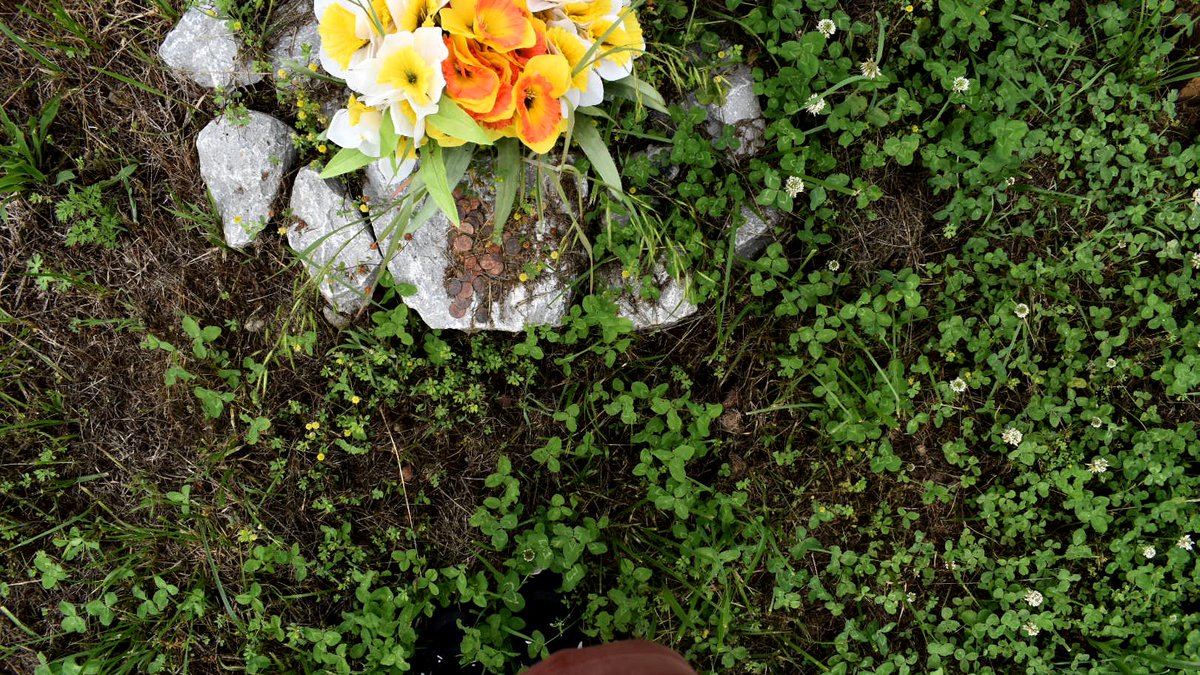 Below it are two American flags, faux buttercups, and a granite rock with pennies on it. Those pennies symbolize the lives of the workers. Ansol’s wife Janie told me she chose one-cent coins because the lives of the workers “were not worth one penny to corporate America.”